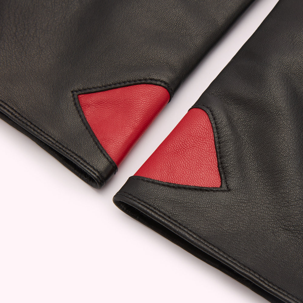 Close-up of black leather gloves with red triangular accents.
