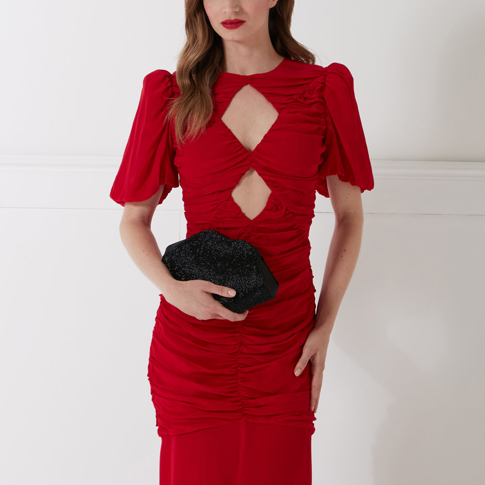 Woman in red dress holding a black beaded clutch.
