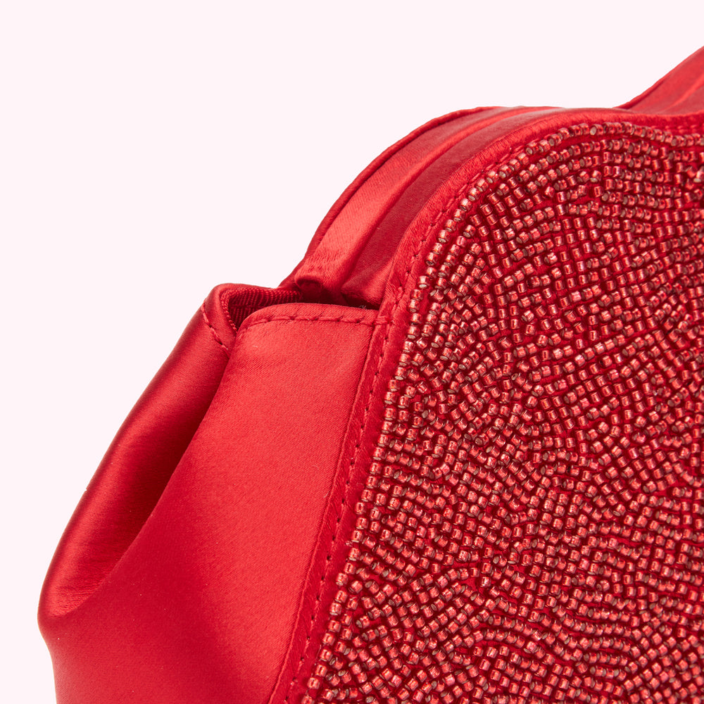 Close-up of a red satin handbag embellished with red beads.
