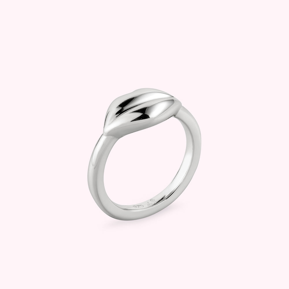 Angle side image of a silver lip shape ring on a white background.