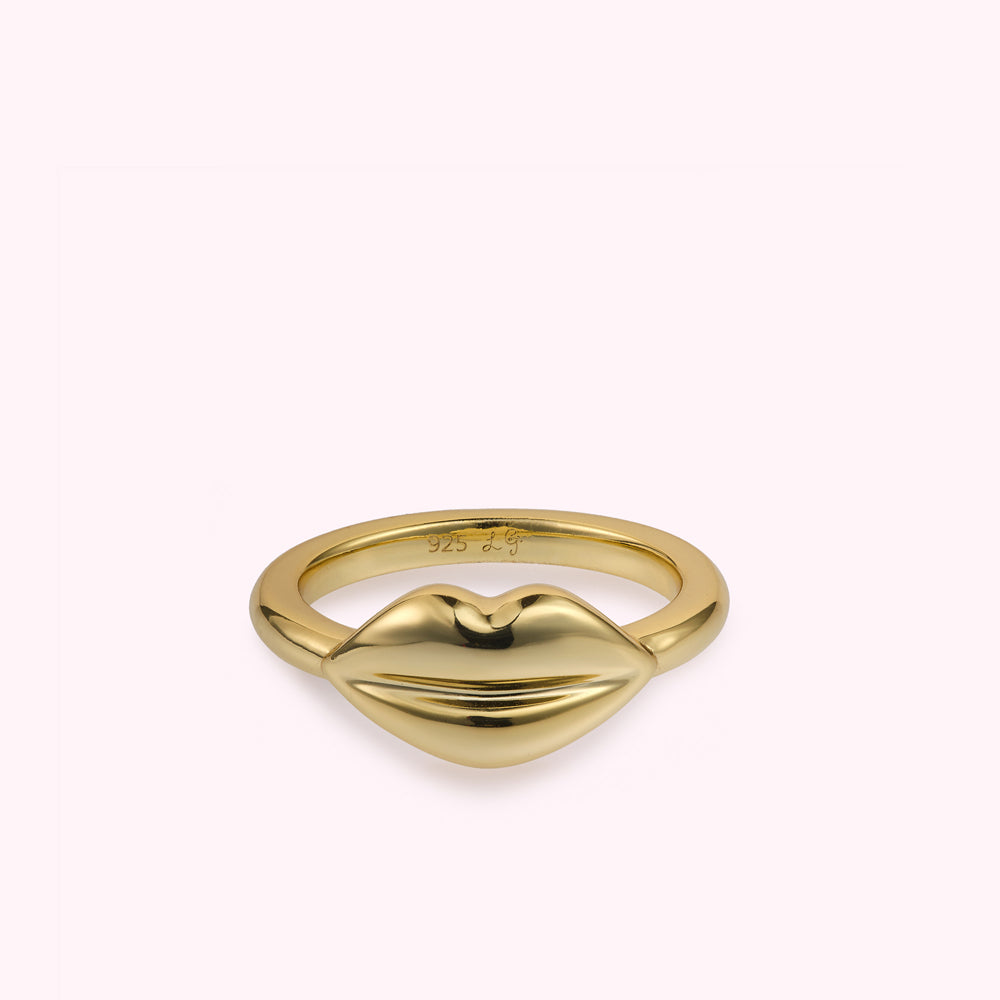 Front on image of a gold lip shape ring flat on a white background.