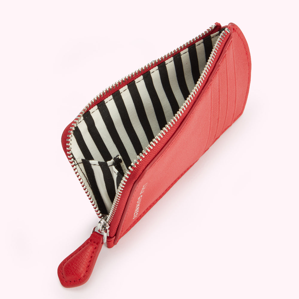 Red leather zip-around coin purse with black and white striped interior.
