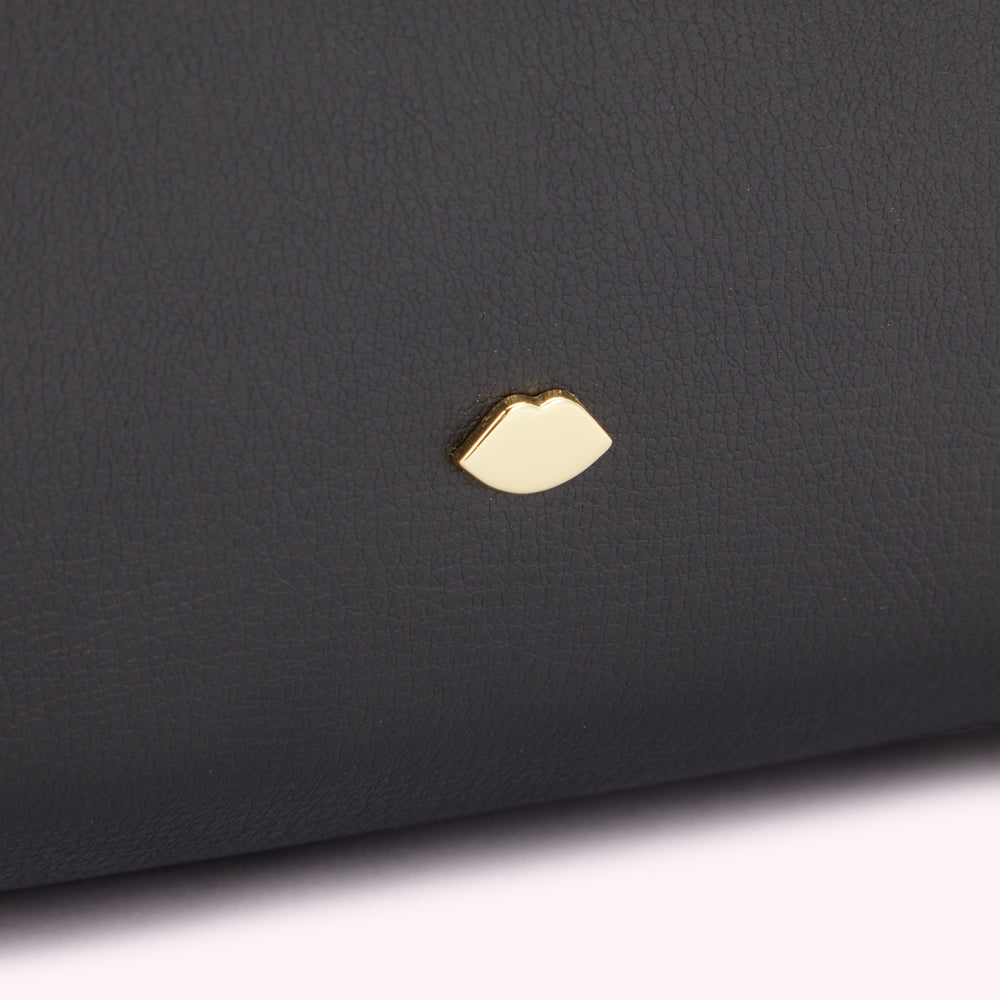 Close up detail of the gold metal lip detail on a black leather bag.