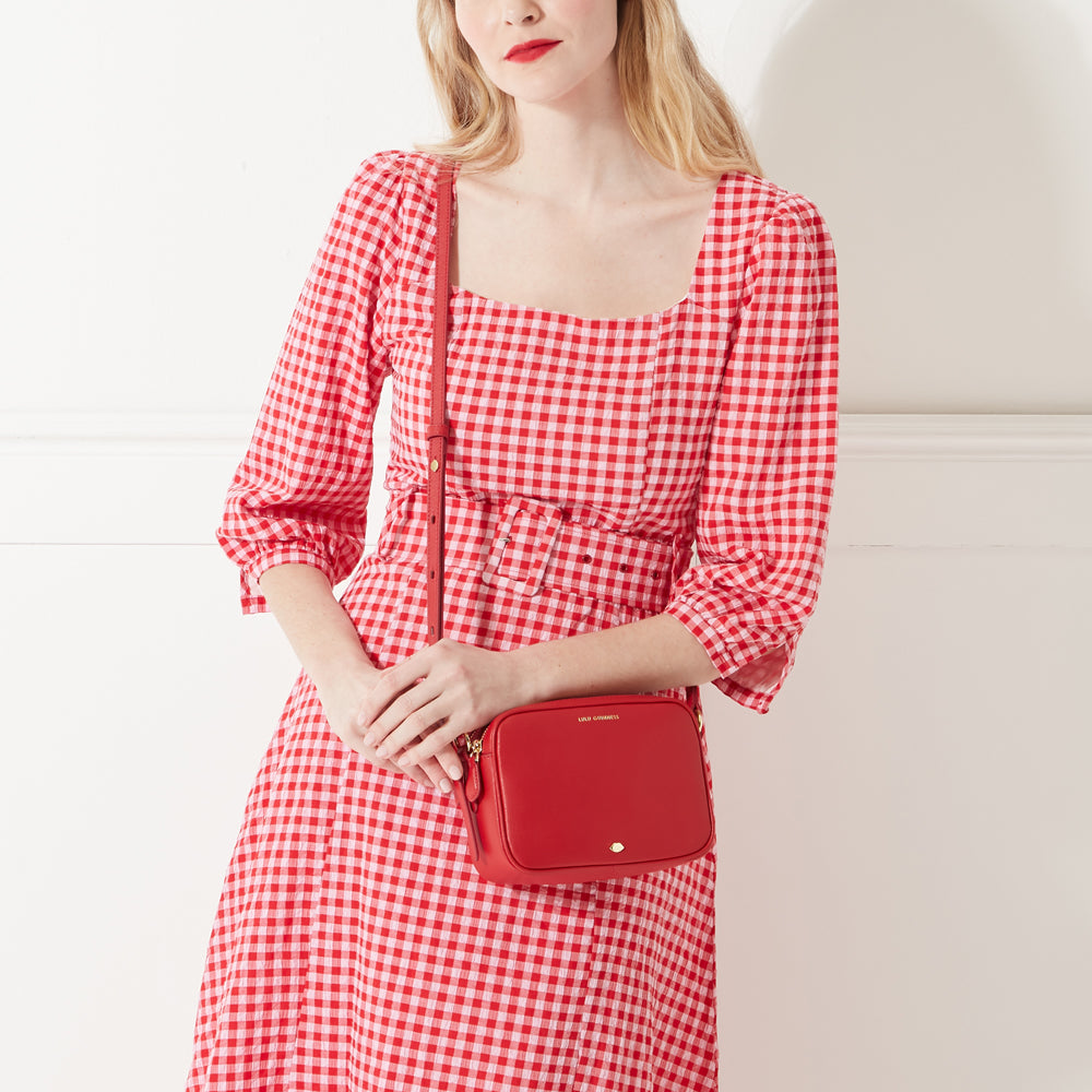 Model wearing a red and white gingham dress with a leather red crossbody bag.