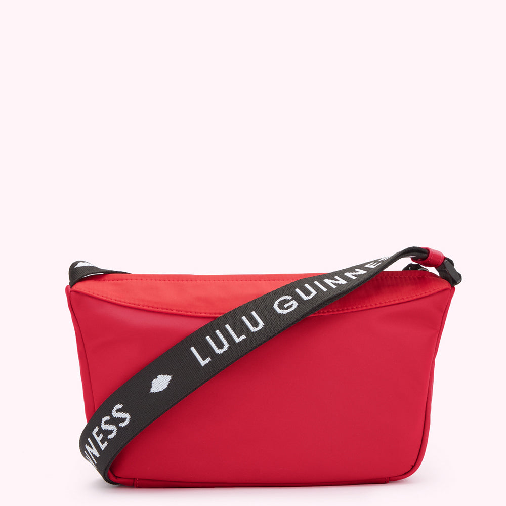 Red and black nylon crossbody bag with "Lulu Guinness" printed on the strap.