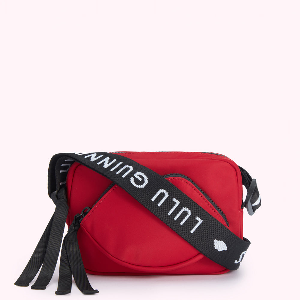 Red crossbody bag with a lip-shaped detail and a black strap with white "Lulu Guinness" lettering.