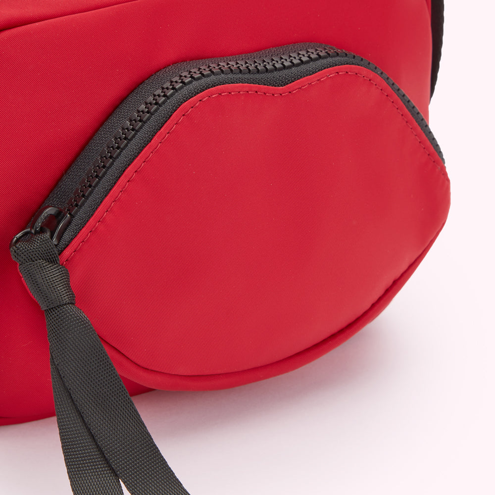 Close-up of a red crossbody bag with a lip-shaped zipper pocket.