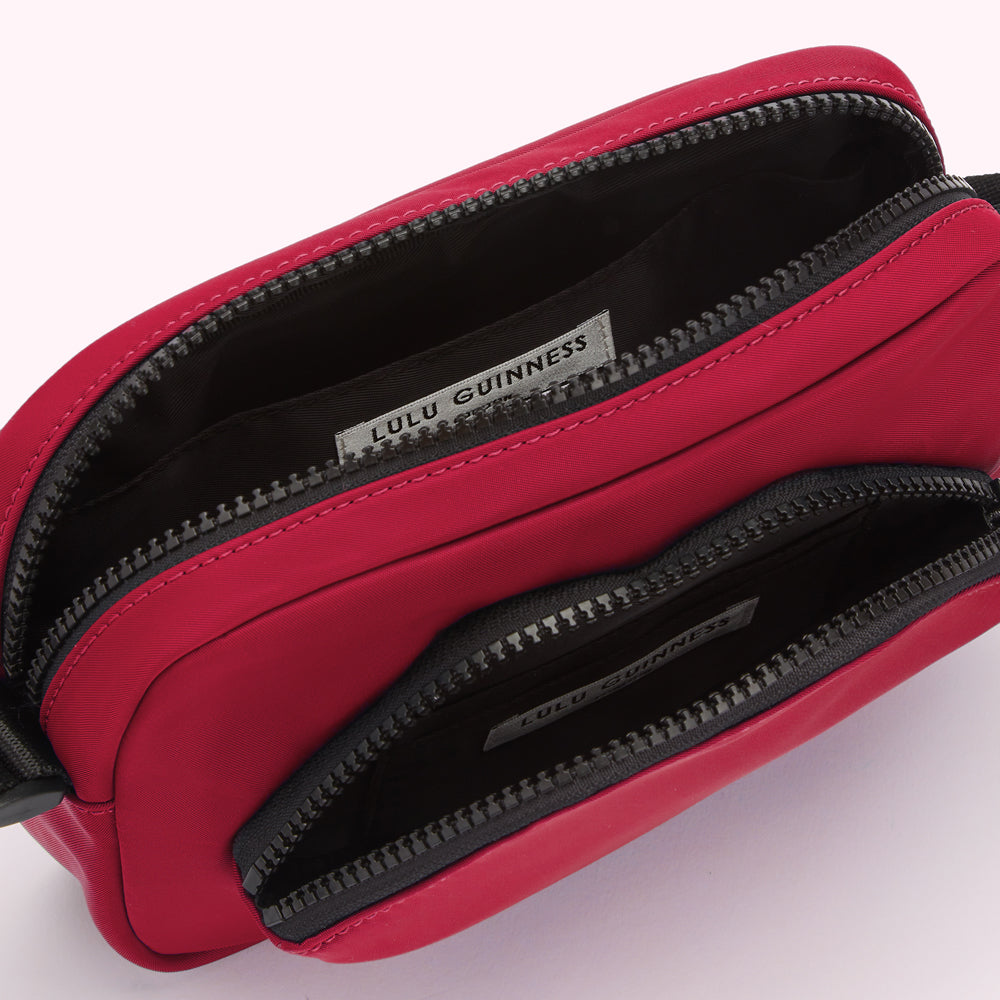 Crimson red Lulu Guinness crossbody bag open to show the interior compartments and branding label.