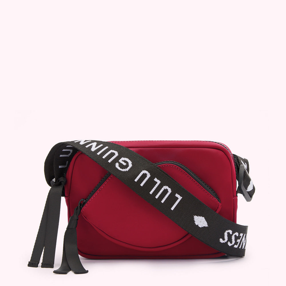 Red crossbody bag with a lip-shaped detail and a black strap with white "Lulu Guinness" lettering.