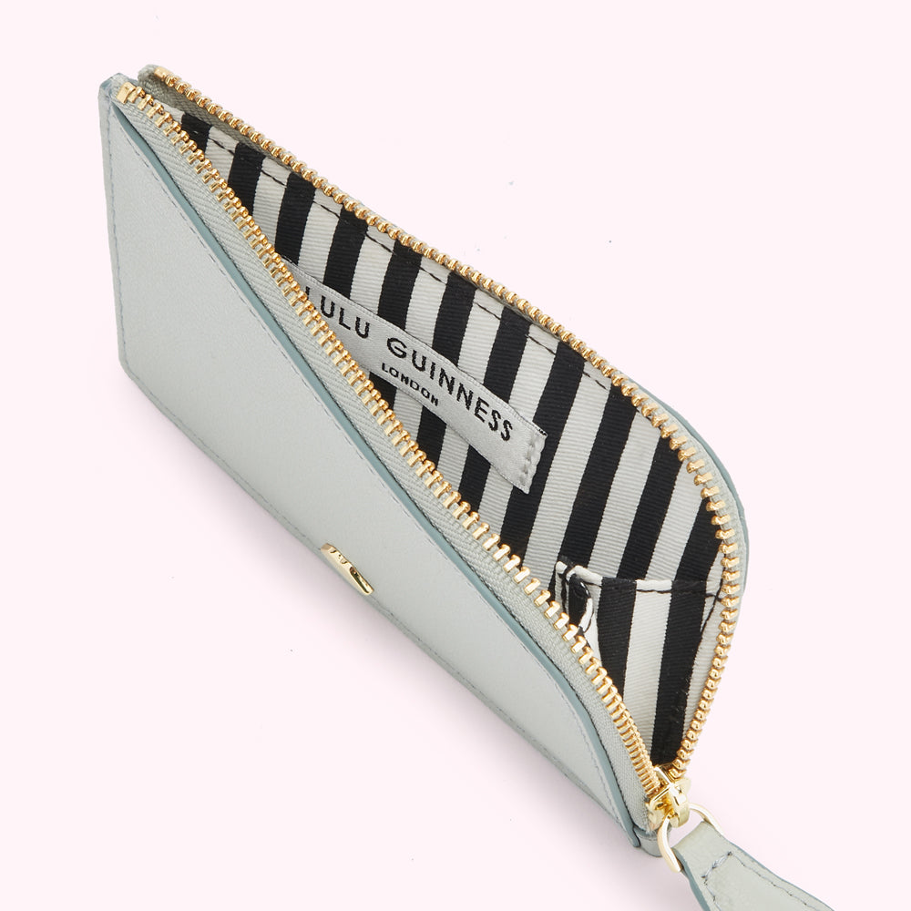 A pale blue Lulu Guinness zip-around cardholder with a black and white striped interior.
