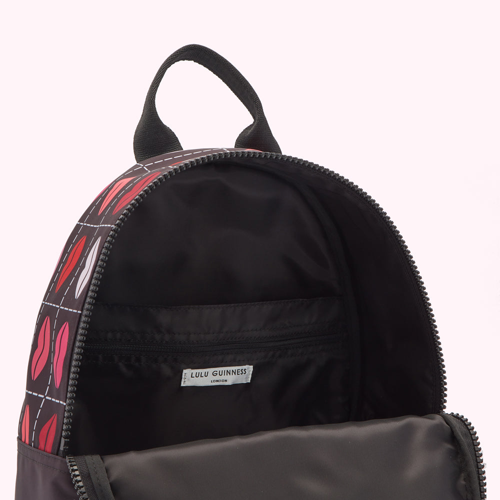 Open Lulu Guinness London backpack with a black interior and a red and pink lips print on the exterior.