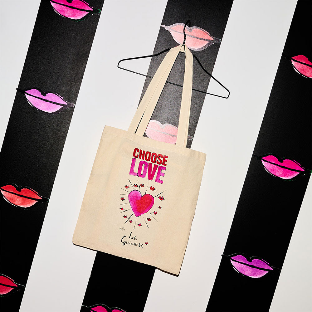 Cotton canvas Choose Love with Lulu Guinness Tote bag on a striped and lip print background.