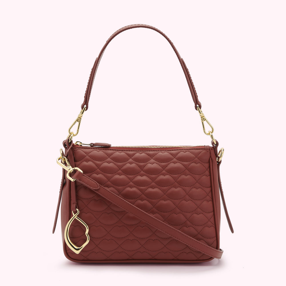 A russet quilted shoulder bag with a gold lip-shaped charm.
