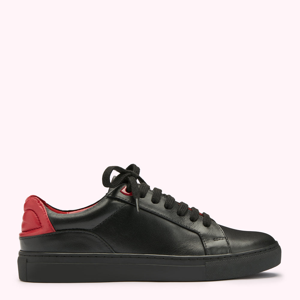 Black leather sneaker with red accent on a white background.
