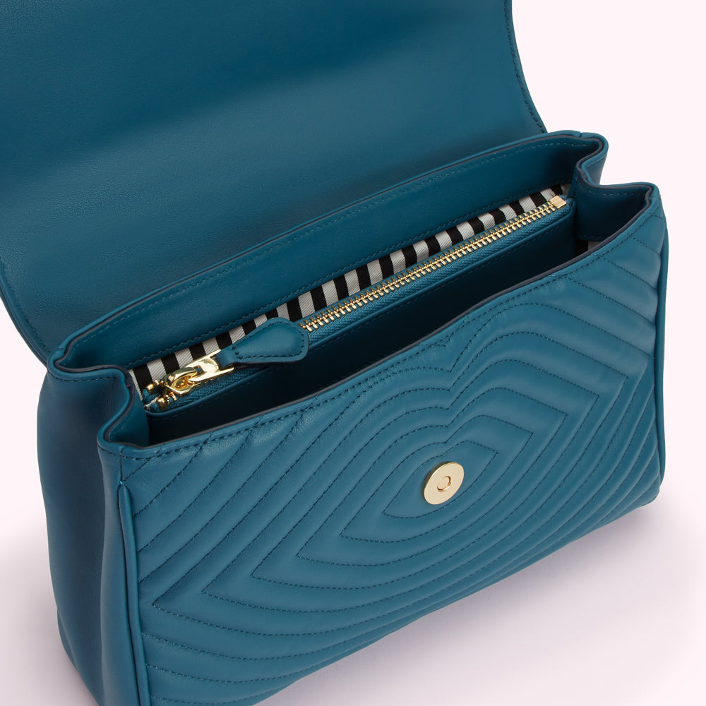 Teal quilted handbag with gold zipper and clasp open to reveal black and white striped interior lining.
