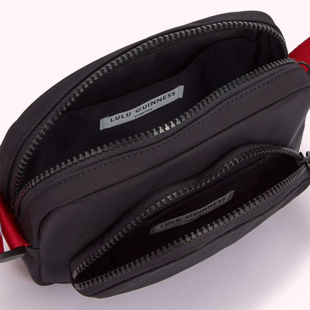 Open black Lulu Guinness London crossbody bag with red strap detailing.