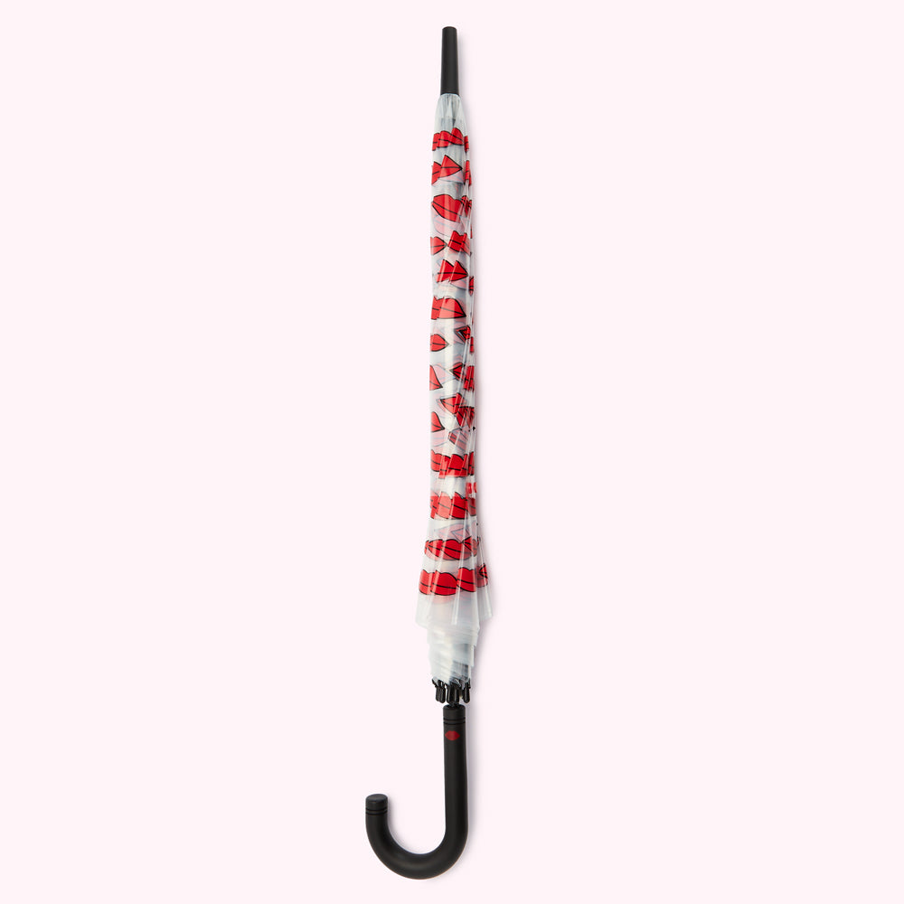 A closed clear umbrella with a black handle and red lips print.