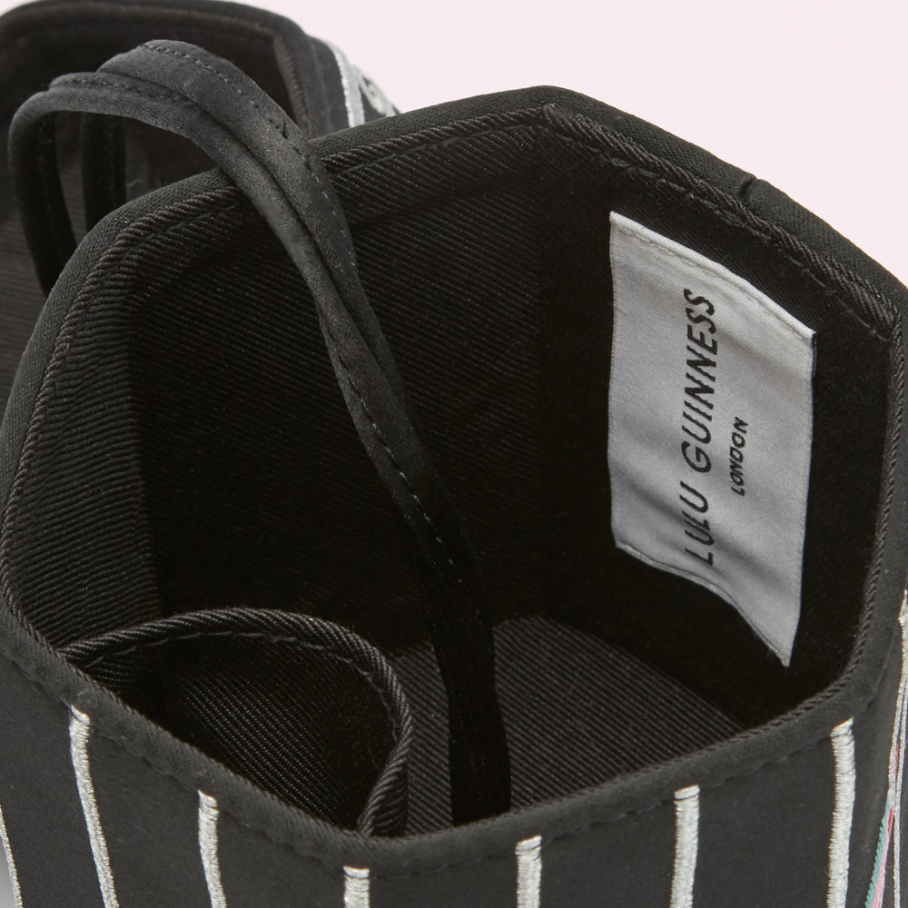 Close-up view of the inside of a black and white striped Lulu Guinness bag, showing the brand label.