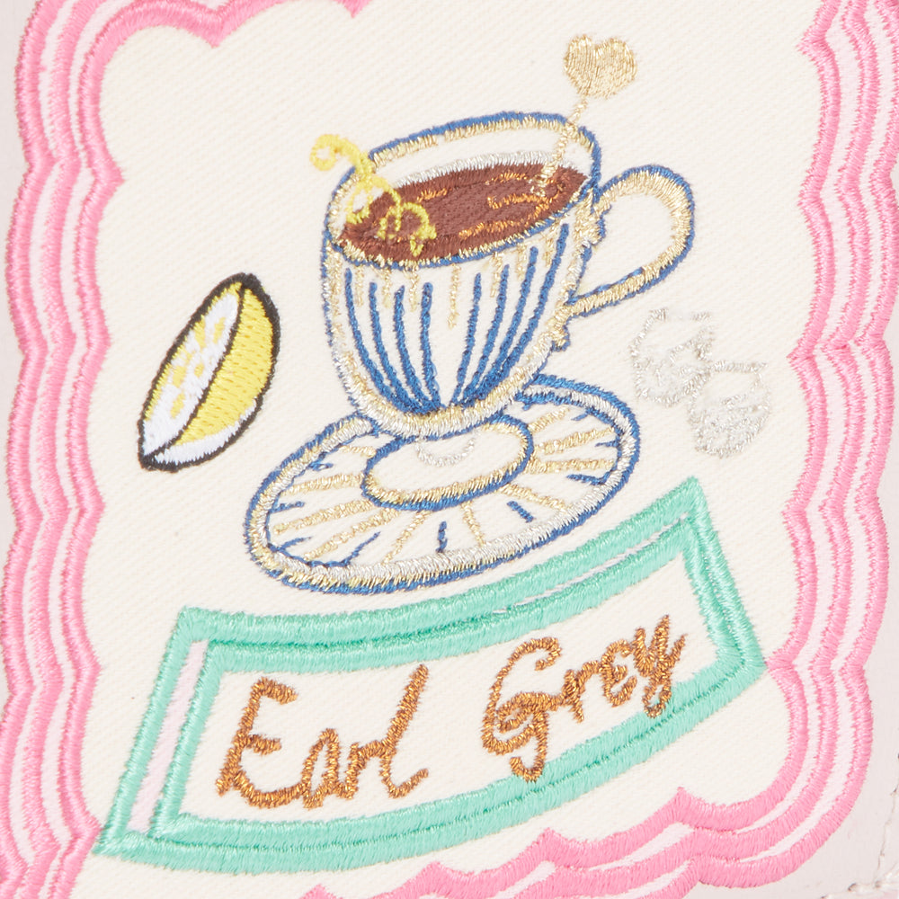 Embroidered patch on off-white background with pink border, depicting a cup of Earl Grey tea with lemon.