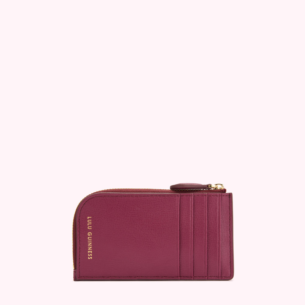 A burgundy Lulu Guinness zip-around cardholder against a white background.
