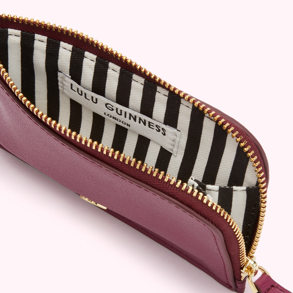 Open burgundy Lulu Guinness zip-around purse with black and white striped lining.
