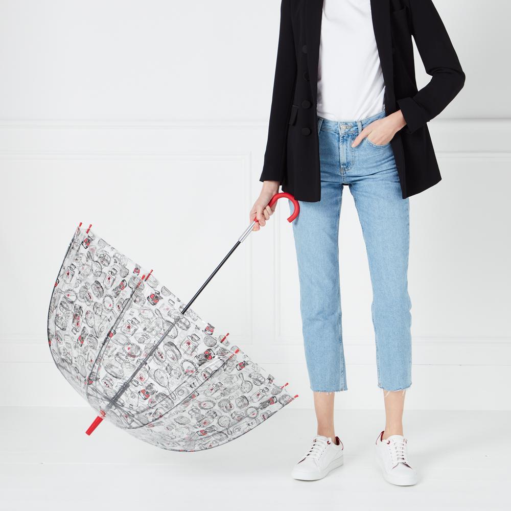 Woman holding a clear umbrella with a black and white pattern, against a white background.
