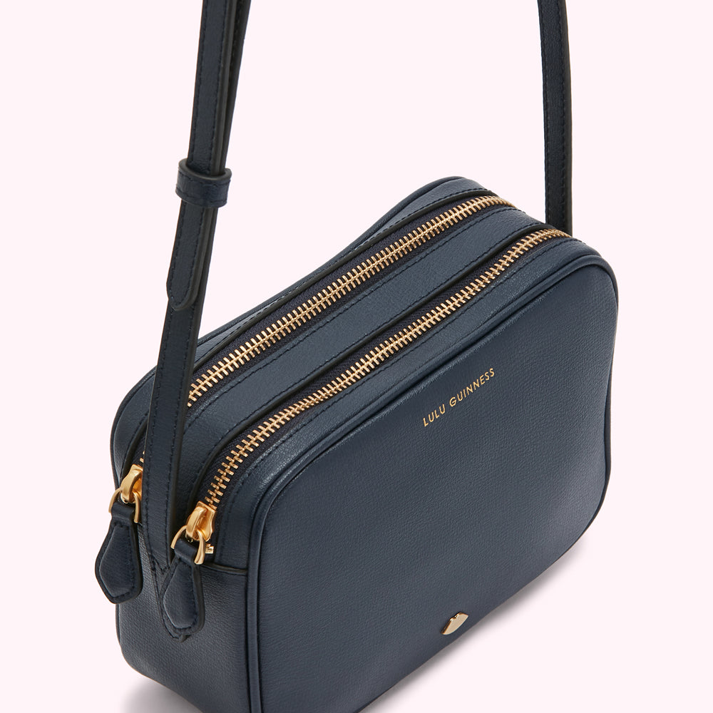 Navy blue Lulu Guinness crossbody bag with gold zippers.