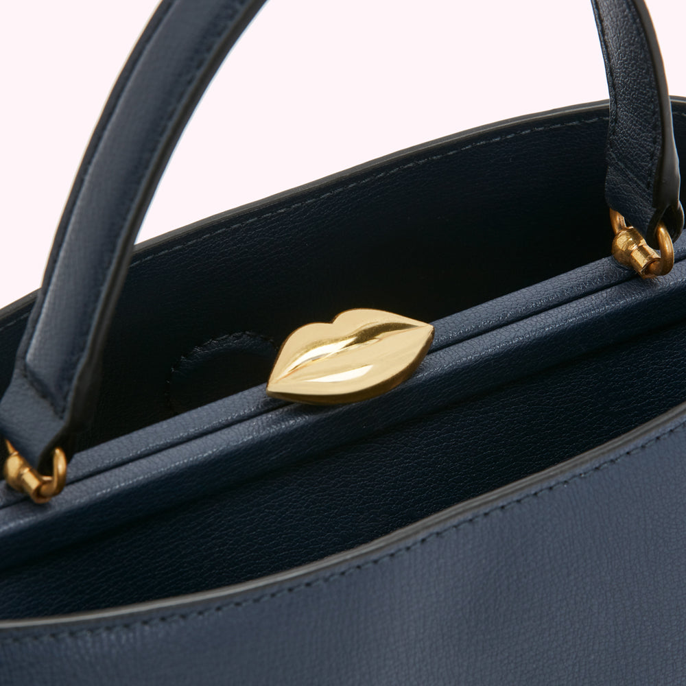 Close-up of the interior of a navy blue leather handbag with a gold lip-shaped clasp.
