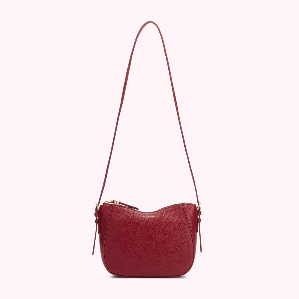 A dark red, semi-circular crossbody bag with a long strap and gold zipper.
