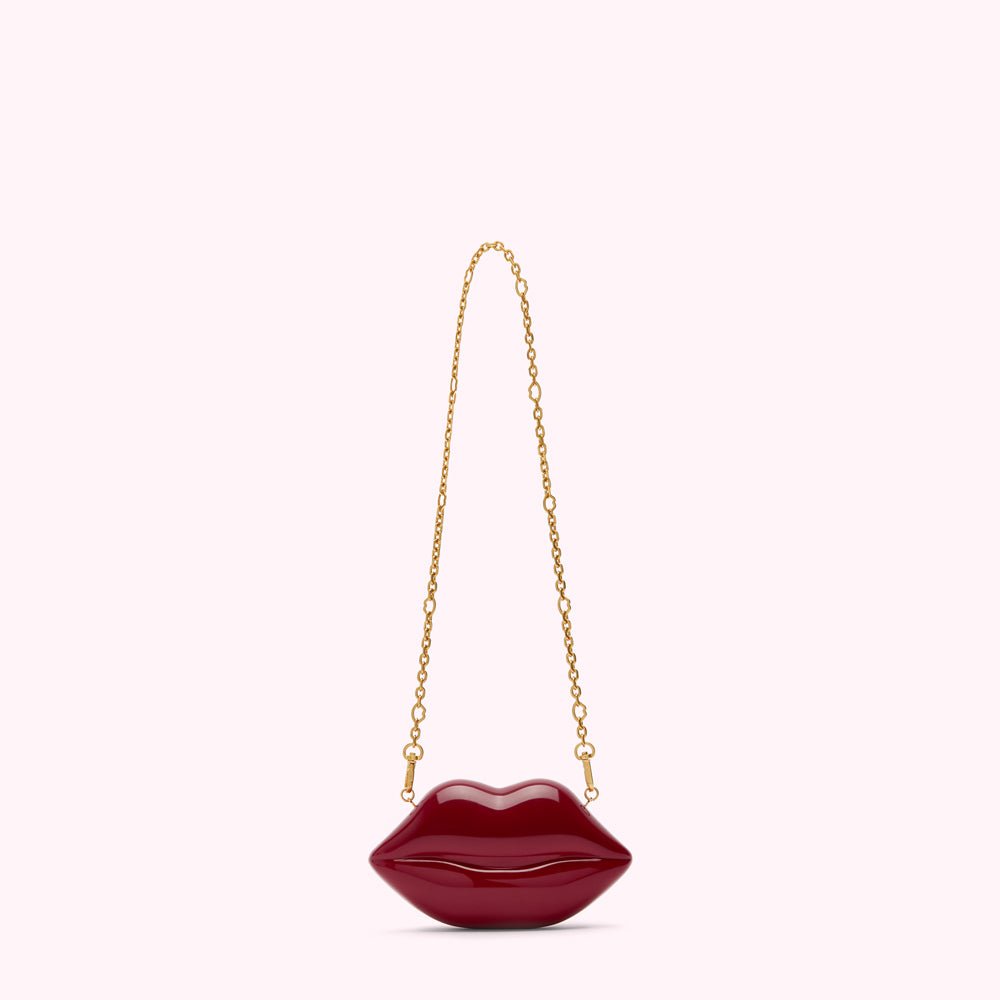 Red lip-shaped purse with gold chain strap against a white background.
