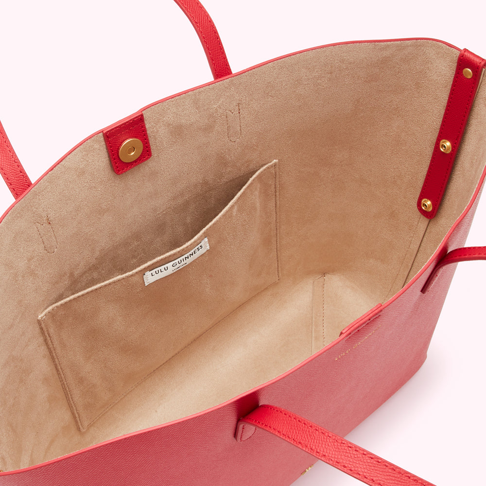 Inside of a red Lulu Guinness tote bag showing a beige interior with a smaller pocket and the brand label.