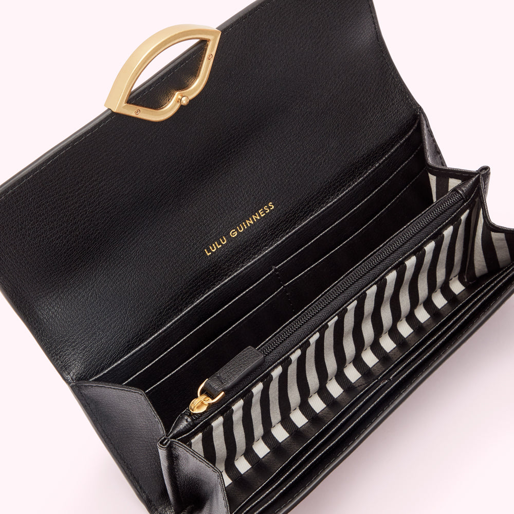 Open black Lulu Guinness wallet with gold clasp and black and white striped interior.
