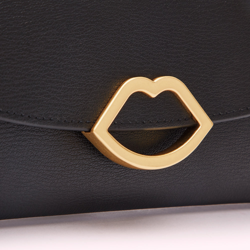 Close-up of a black leather wallet with a gold lip-shaped clasp.
