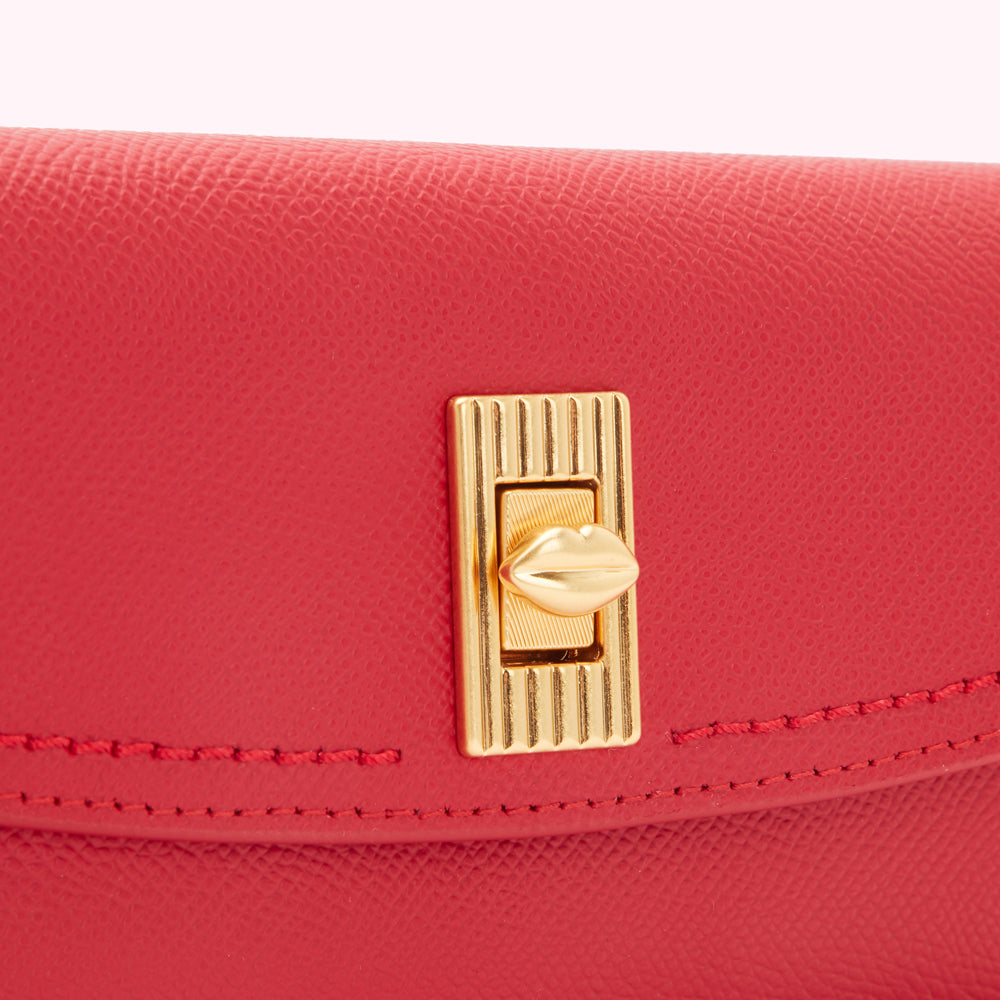 Close-up of a red leather purse with a gold lip-shaped clasp.
