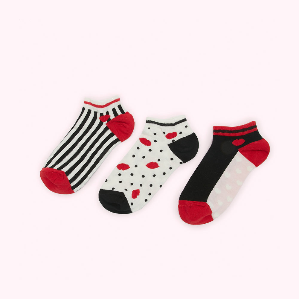 Three pairs of ankle socks with different patterns: black and white stripes, black and white polka dots with red lips, and black and white polka dots with red lips. The socks have red heels and toes.