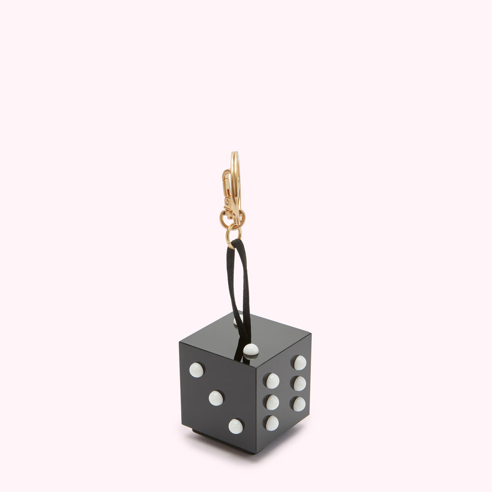 Black die-shaped keychain with white dots against a white background.
